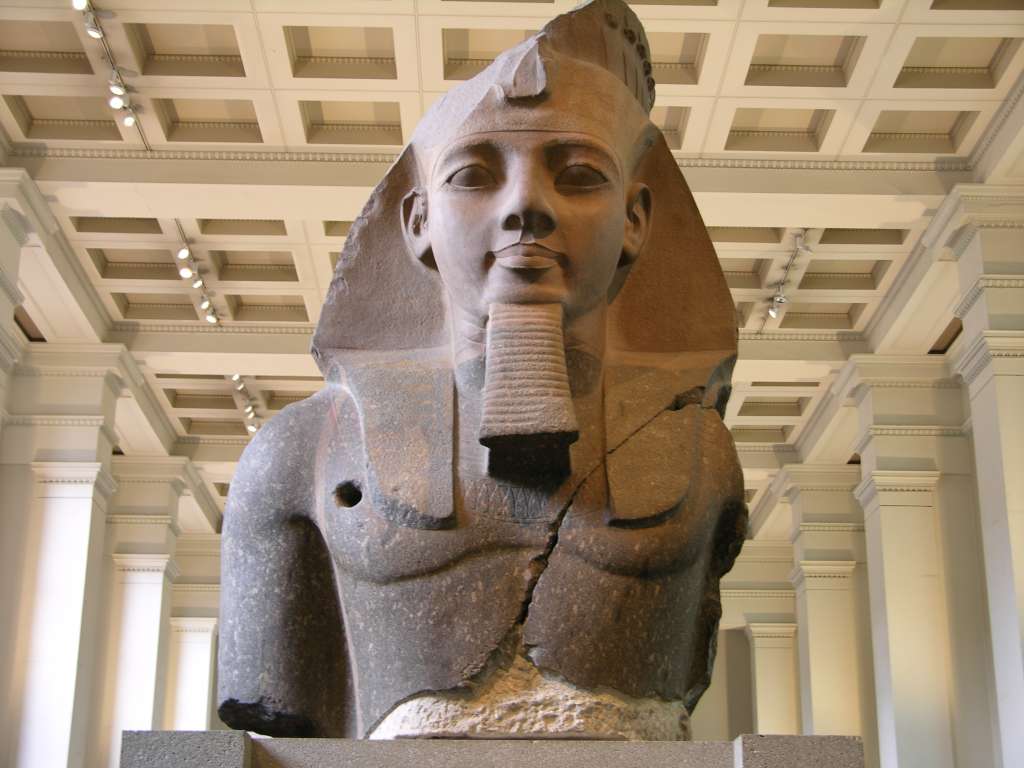 British Museum Top 20 02-2 Colossal Bust of Ramesses II 2. Ramesses II bust � Thebes, 1250BC, 267cm high. This fragment of the statue of Ramesses II (1279-1213 BC) was cut from a single block of two-coloured granite. The sculptor has used a slight variation of normal conventions to relate his work to the viewer, angling the eyes down slightly, so that the statue relates more to those looking at it. He is shown wearing the nemes head-dress surmounted by a cobra diadem. It was retrieved from the mortuary temple of Ramesses at Thebes in 1816.